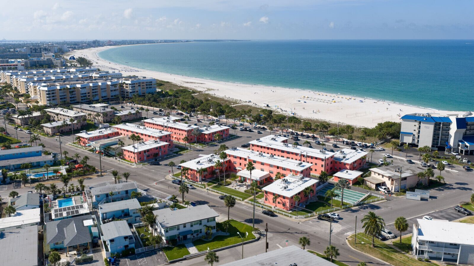 A coastal hotel area with multiple buildings, a beach, and a clear view of the ocean.