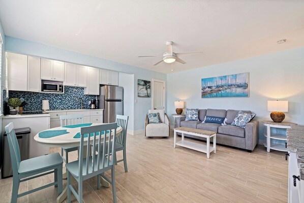 A modern kitchen with white cabinets, a stainless steel refrigerator, and a blue tiled backsplash.
