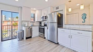 A modern kitchen with white cabinets, stainless steel appliances, and a view of the outdoors. - Beach-Goers Paradise Getaway! Pool! Sun! Fun! (St. Pete Beach)