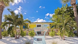 A sign for UPHAM BEACH with a stone wall and palm trees in the foreground. - Prime St Pete Beach Spot • Private Patio (St. Pete Beach)