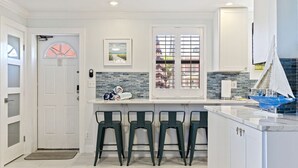 A modern kitchen with a white door, a window with a view, and a small sailboat model. - Poolside Paradise with Patio, Steps from Beach (St. Pete Beach)