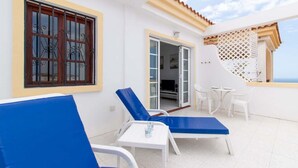 A balcony with blue lounge chairs, a small table, and a white chair. - Terrace View Studio (Costa Adeje)