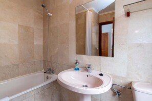 Un baño con bañera, lavamanos e inodoro.