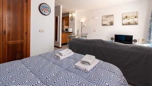 A hotel room with a large bed, a wooden wardrobe, a kitchen area, and a TV. - Terrace View Studio (Costa Adeje)
