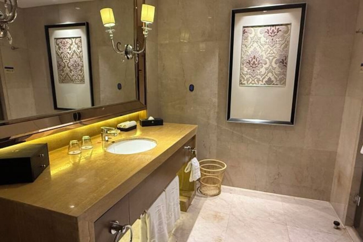 Een moderne badkamer met een houten wastafelmeubel, een grote spiegel en lijstwerken aan de muur.