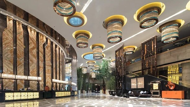 Eine moderne Lobby mit Marmorwand, einer Rezeption und einer Treppe.