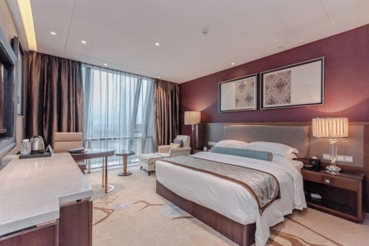 Een moderne hotelkamer met een groot bed, een bureau en uitzicht op de stad.
