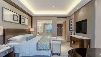 Een moderne hotelkamer met een groot bed, nachtkastjes, een flatscreen televisie en een badkamer met glazen wanden.