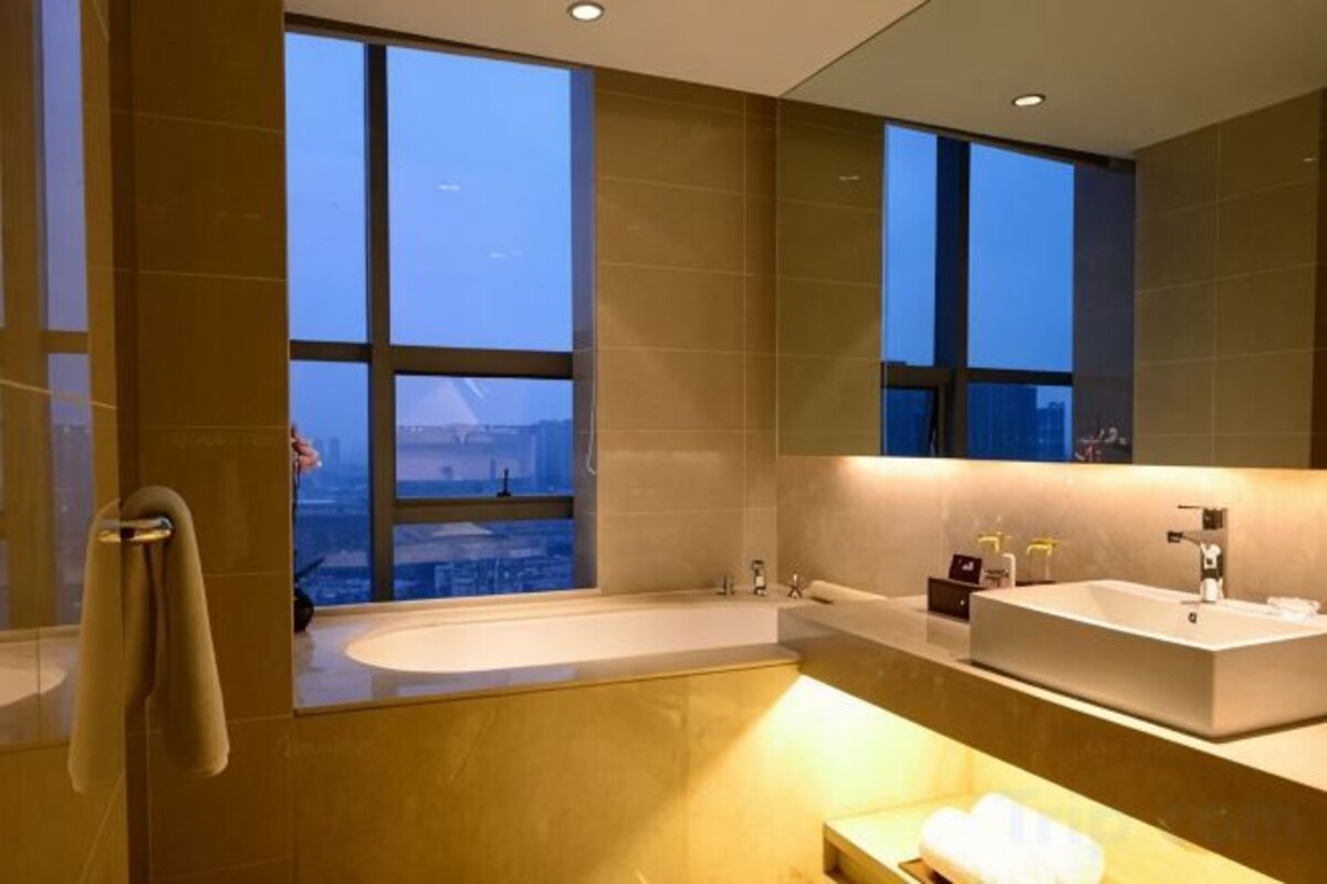 A modern bathroom with a large bathtub, a sink, and a mirror.