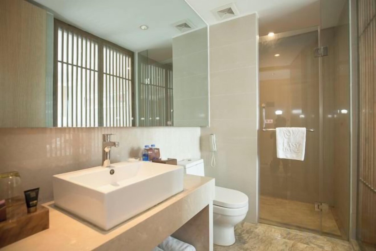 A modern bathroom with a large mirror, a white sink, and a glass-enclosed shower.