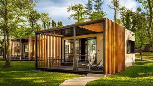 Un bâtiment moderne, de plain-pied, doté d’une façade en bois et de grandes fenêtres, entouré d’une pelouse et d’arbres.