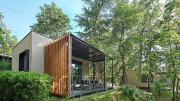 A modern building with a wooden structure, a covered outdoor area, and a garden setting.