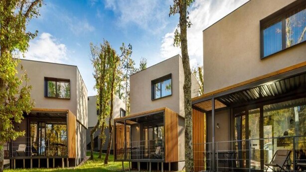 Un bâtiment moderne doté de nombreuses pièces, de grandes fenêtres et d’une cour verdoyante.