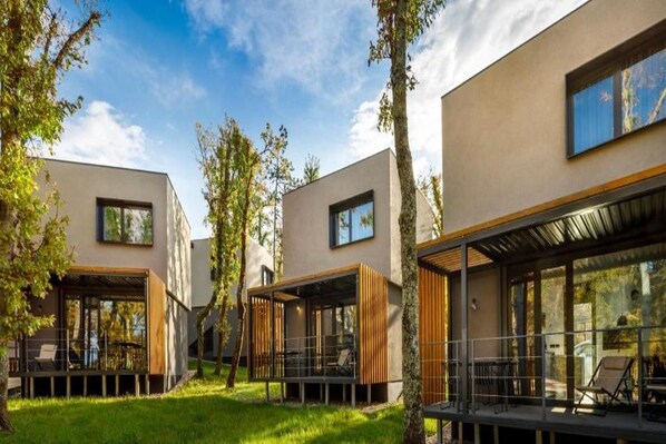 Un bâtiment moderne doté de nombreuses pièces, de grandes fenêtres et d’une cour verdoyante.