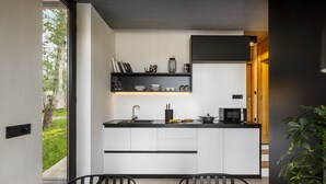 Une cuisine moderne avec des armoires blanches, des comptoirs noirs et un pare-feu noir. On y trouve également un coin repas avec une table et des chaises en bois.