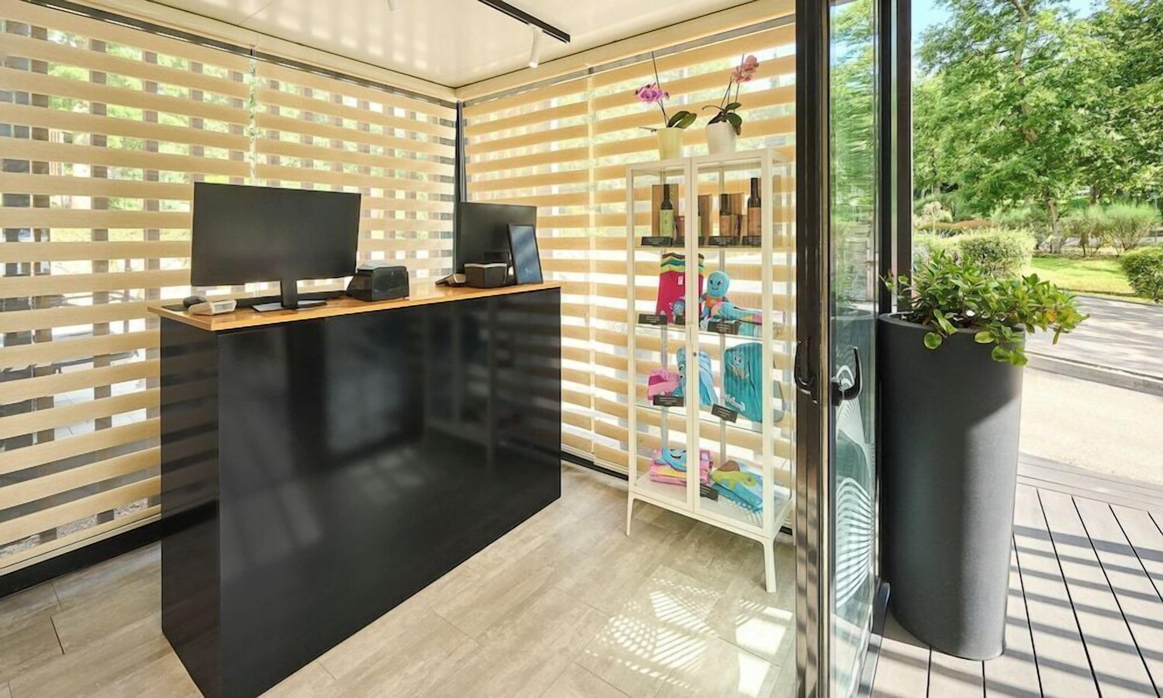 A reception area with a flat-screen TV, a wooden desk, and a glass display case with various items.