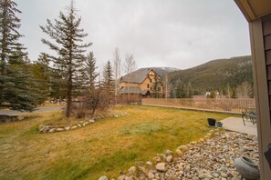 A house with a stone foundation, a wooden deck, and a view of a mountain range. - Red Hawk Lodge 2211 (Keystone)