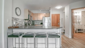 A modern kitchen with a central island, stainless steel appliances, and a wooden door leading to a bathroom. - Silver Mill 8225 (Keystone)