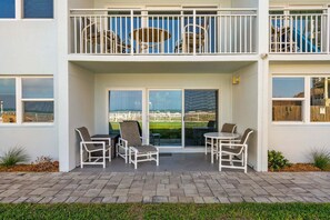 A two-story building with a balcony, outdoor seating, and a view of a fenced area.
