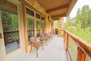 Relax on the balcony with a view of the forest and building beyond.