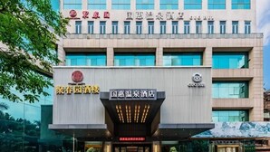 A hotel with a modern facade, featuring a prominent entrance with illuminated signage and a large logo. - Guohui Hot Spring Hotel (Fuzhou)