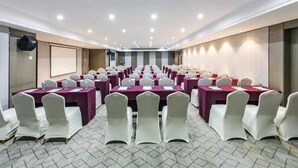 A conference room with rows of tables and chairs, equipped with water bottles and nameplates, and a projector screen on the wall. - Guohui Hot Spring Hotel (Fuzhou)