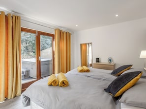 A hotel room with two beds, a balcony, a desk, and a lamp.