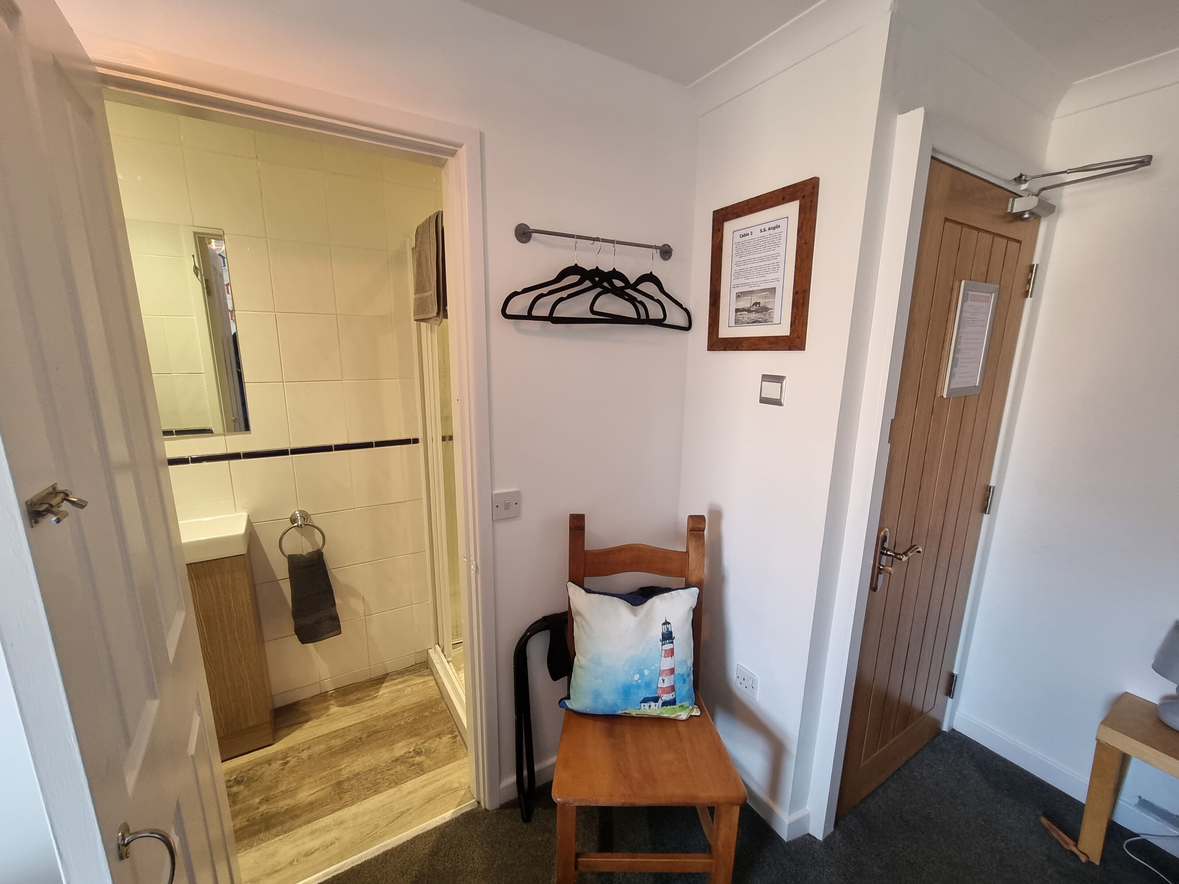 Un bagno con doccia, un portasacchi e una panca in legno.