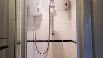 Ducha con cabezal de ducha de mano, dispensador de jabón en la pared y mampara de vidrio.