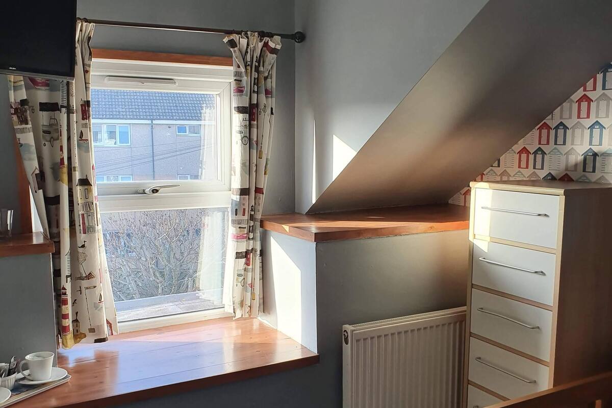 A bedroom with a window, a bed, a dresser, and a radiator.