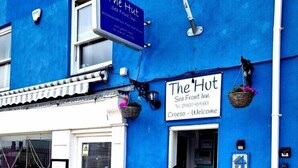 A blue building with a sign reading "The Hot Sea Front Inn" and a welcome sign.