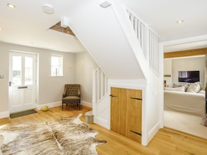 A spacious room with a wooden floor, a white staircase, a large window, and a television. - 3 bedroom accommodation in York (York)