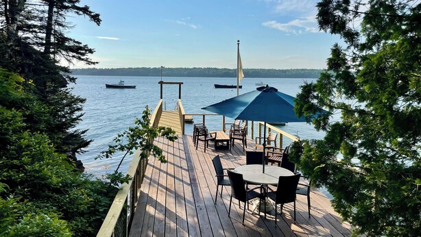 Una terraza de madera con mobiliario exterior y vista al agua.