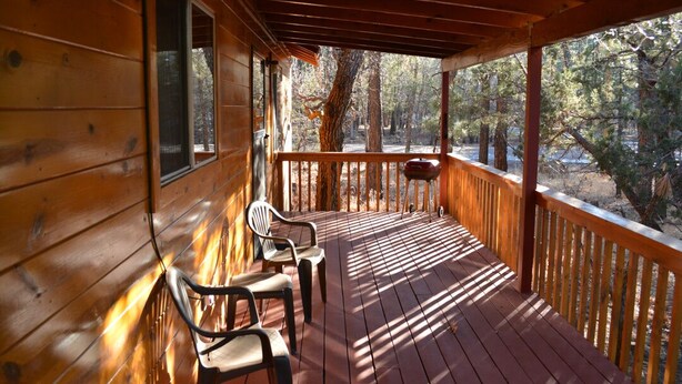 Une terrasse en bois avec des chaises et un luminaire suspendu.