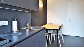 Eine moderne Küche mit grauen Schränken, einer Edelstahl-Spüle und einem Holztisch mit zwei Stühlen.