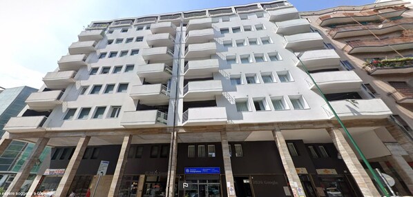 A multi-story building with balconies, a Google sign, and a visible storefront at the ground level. - Venice Terminal Apartments & Suites (Mestre)