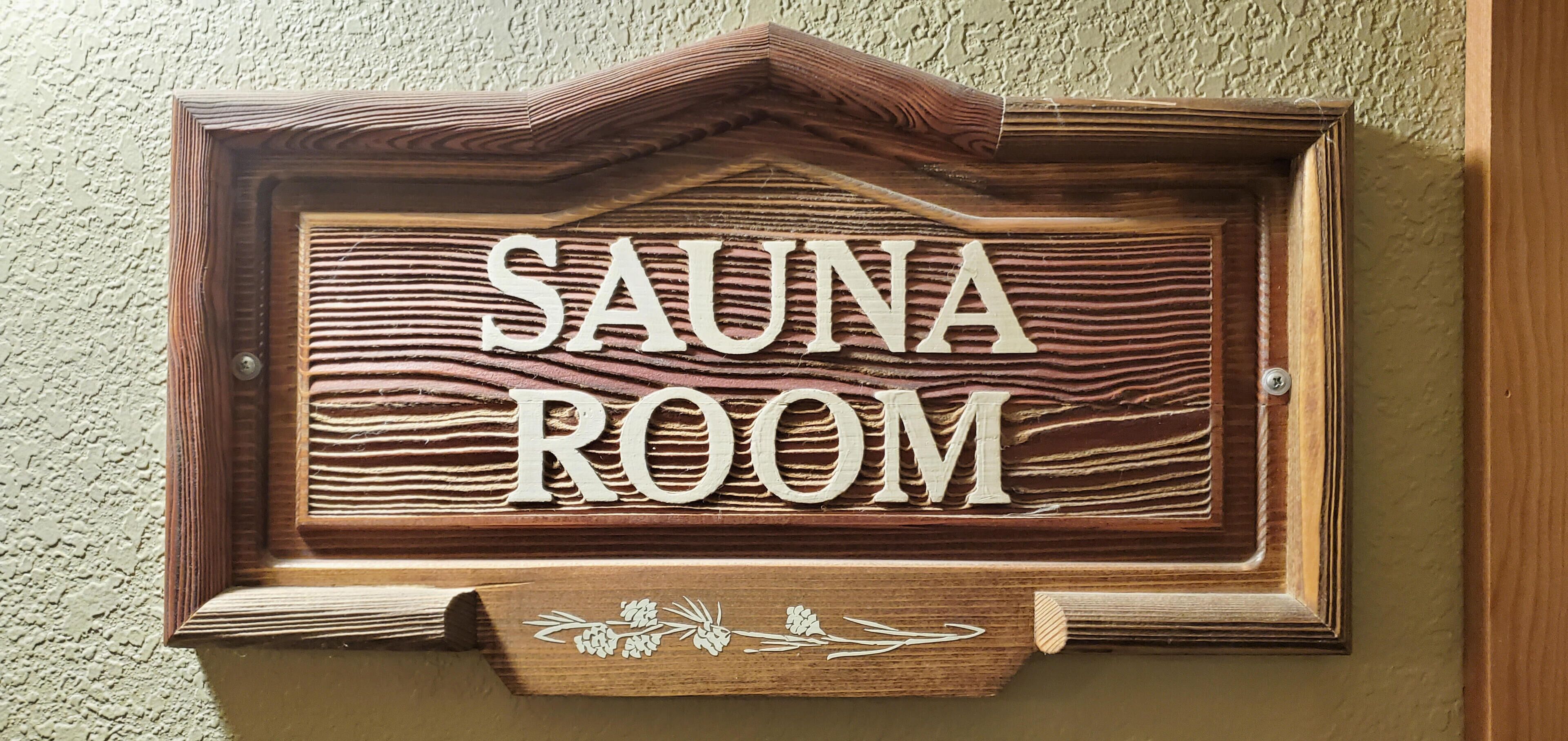 A wooden sign with the words "SAUNA ROOM" indicating a designated area for sauna use.