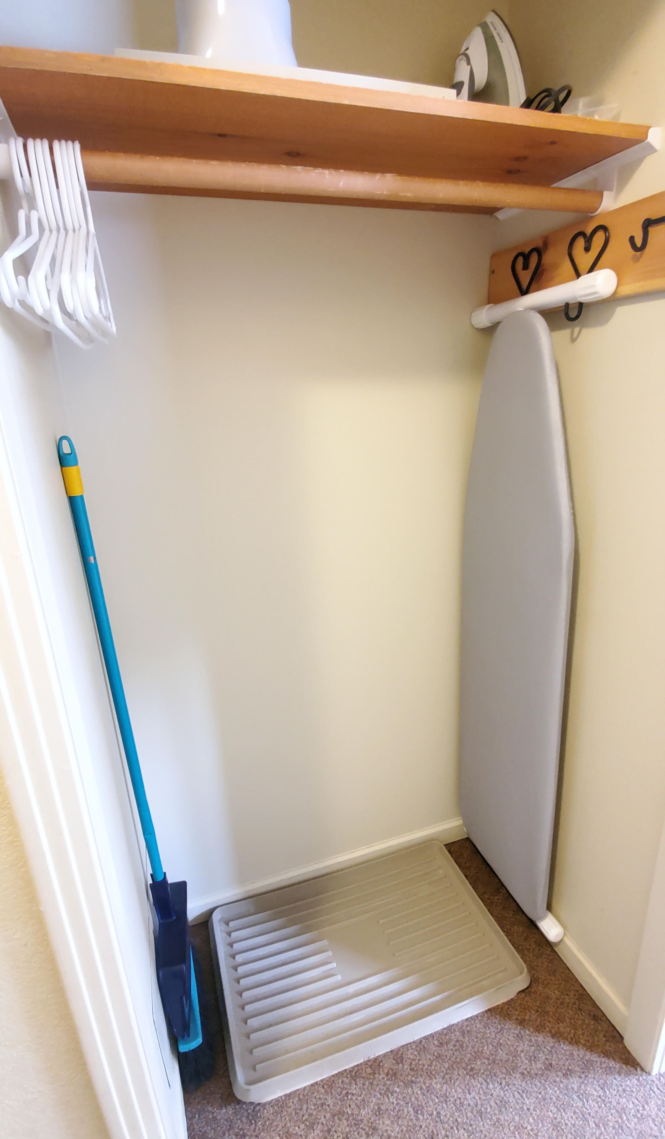 Een hoek van een kamer met een dweil, een bezem en een radiator.