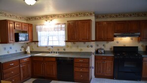Una cocina con armarios de madera, lavavajillas, estufa y microondas.