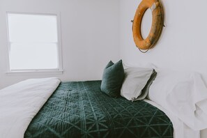 A bed with a green quilt, white pillows, and a white blanket.