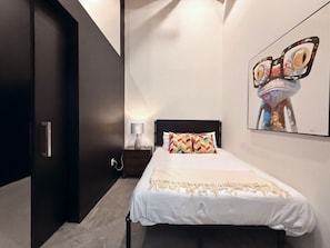 A bedroom with a bed, a nightstand, a wall-mounted lamp, and a framed picture. - 5 miles to Disney • Parking • Dogs Ok • Gym • W/D • AC (Santa Ana)