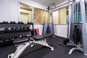A gym with dumbbells, a bench, and weight machines.