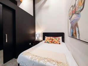 A bedroom with a bed, a nightstand, a lamp, and a painting on the wall. - Stylish Downtown Loft Near Disney (Santa Ana)