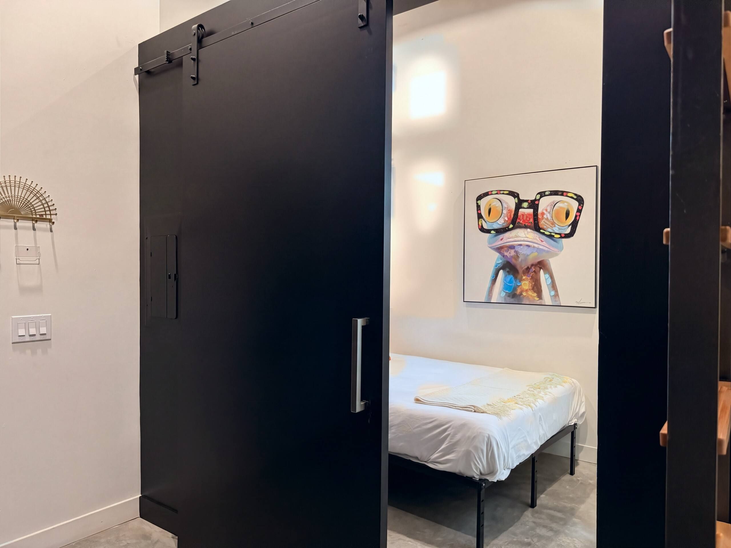 Ein modernes Schlafzimmer mit einem Bett, einer Tür und einem an der Wand befestigten Kunstwerk.
