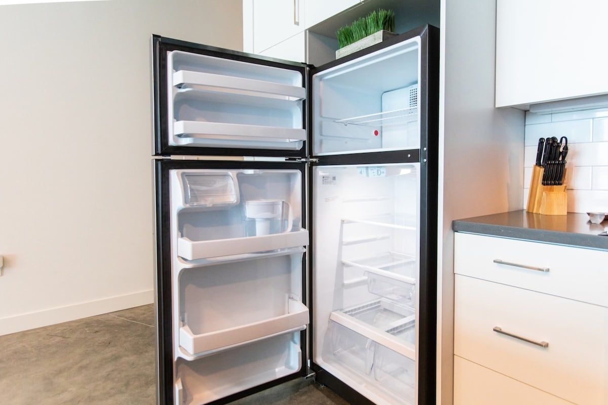 A modern kitchen with a built-in refrigerator, a countertop with kitchen utensils, and a white cabinet.