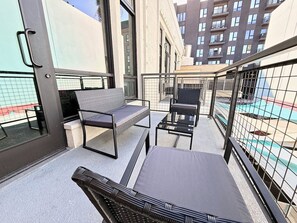 An outdoor balcony with seating and a view of a building. - 5 miles to Disney • Parking • Dogs Ok • Gym • W/D • AC (Santa Ana)
