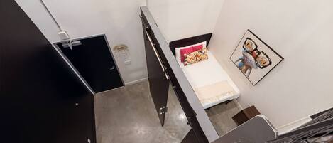 Ein modernes Zimmer mit einem Bett, einem kleinen Tisch und einem gerahmten Bild an der Wand.