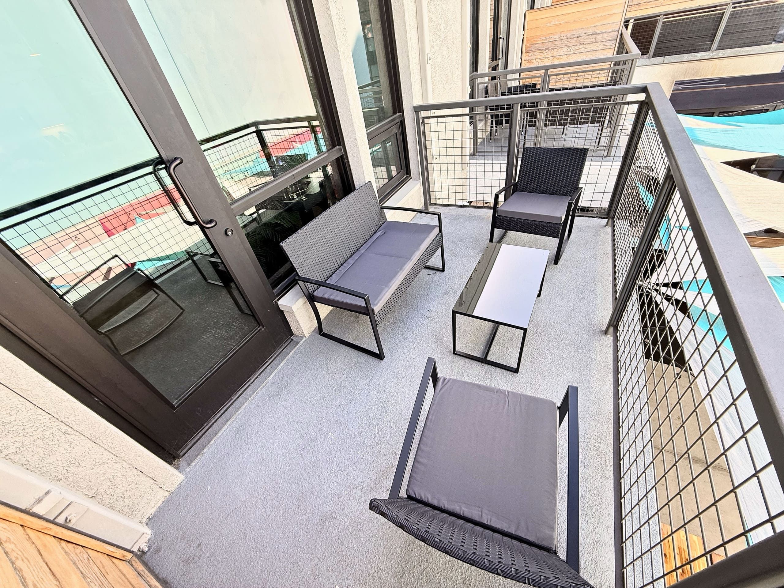 Ein Balkon mit einer Couch, Stühlen und einem kleinen Tisch, umgeben von Metallgeländern.