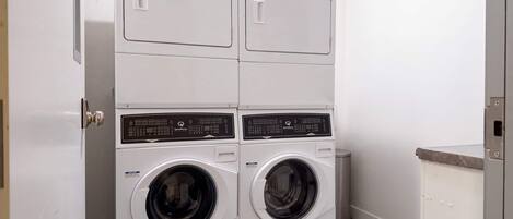 Une petite buanderie compacte, dotée de deux portes, avec une machine à laver et un sèche-linge intégrés.