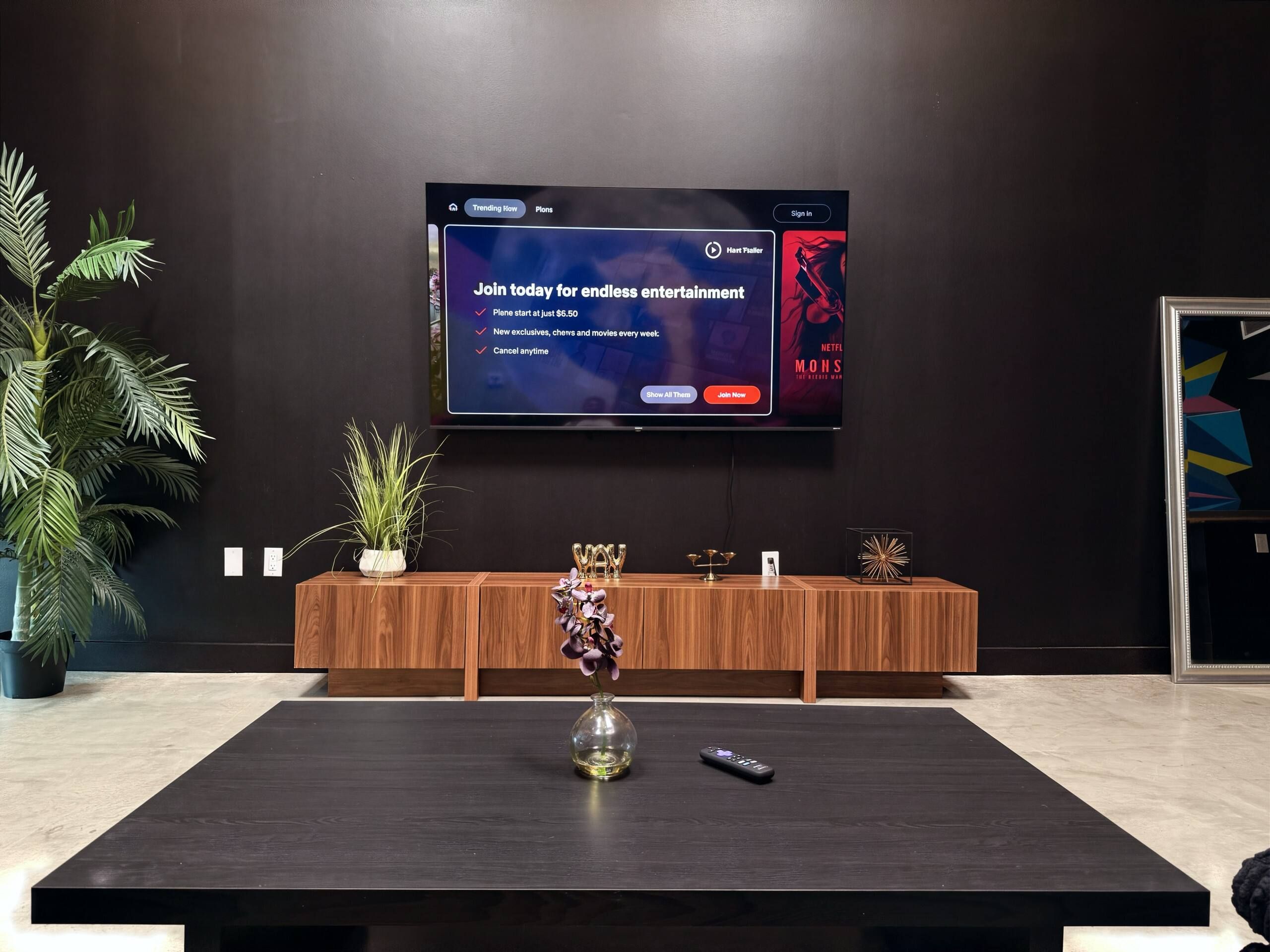 Una sala de estar moderna con un televisor de pantalla plana montado en la pared, un mueble de madera debajo y una mesa de centro de madera oscura al frente.